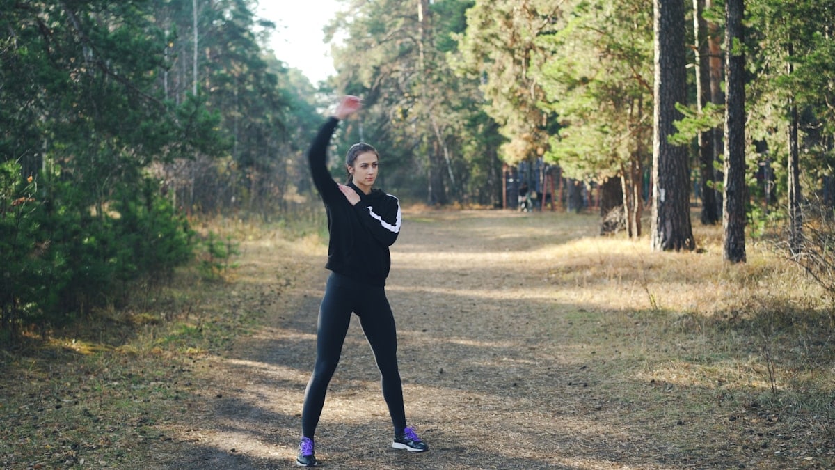 Woman stretching in a forest path.